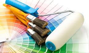 Paint roller, brushes, and colorful paint swatches fanned out on a surface